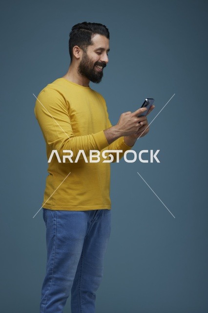 شاب سعودي يستخدم الهاتف الذكي بملابس كاجوال صفراء