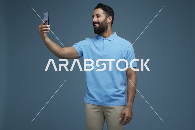 شاب سعودي بقميص بولو أزرق يلتقط سيلفي بالجوال