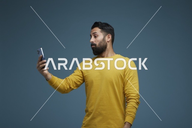 شاب سعودي يلتقط سيلفي بالهاتف الذكي بملابس كاجوال صفراء