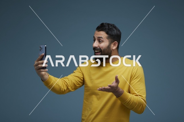 شاب سعودي يلتقط سيلفي بالهاتف الذكي بملابس كاجوال صفراء