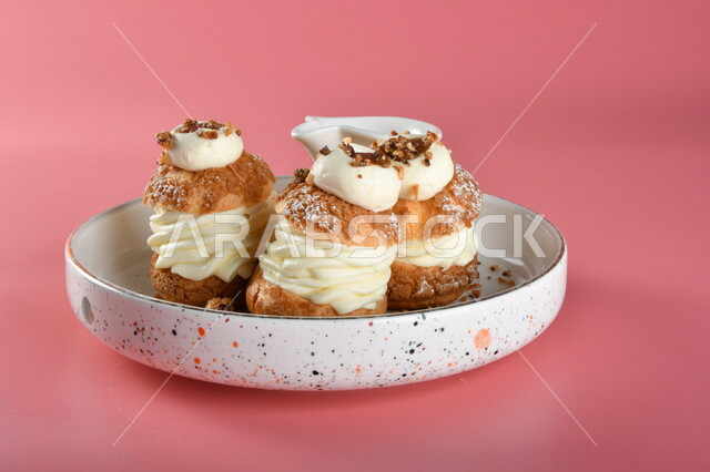 A plate of cold sweets decorated with cream and chocolate sauce on the side, oriental sweets, Ramadan sweets, sweets and sugars, delicious sweets, sweets, delicious cold sweets