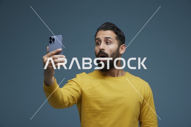 شاب سعودي متفاجئ ينظر إلى الهاتف الذكي