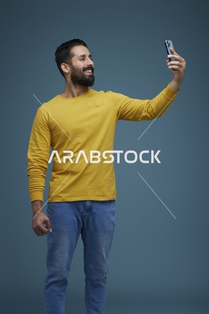 شاب سعودي يلتقط سيلفي بملابس كاجوال وقميص أصفر