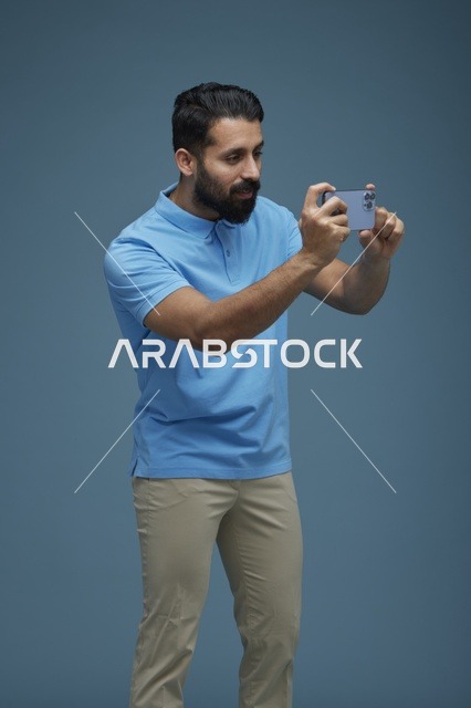 شاب سعودي يصور بالهاتف الذكي بخلفية زرقاء