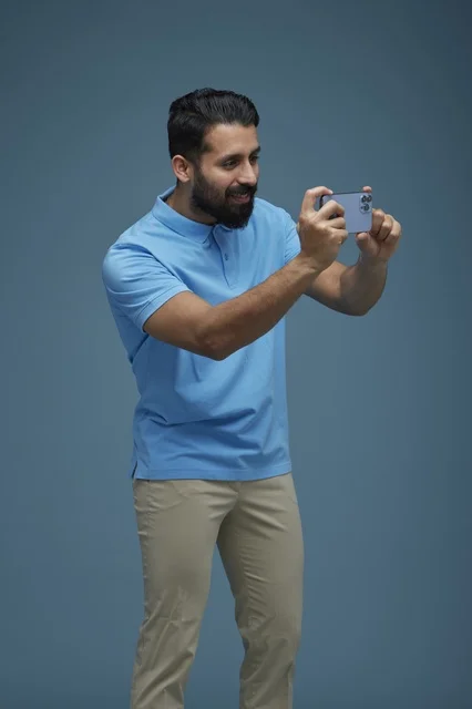 Saudi Man Using Smartphone on Solid Blue Background