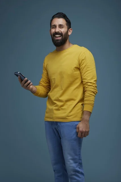 شاب سعودي مع هاتف ذكي يضحك في الاستوديو