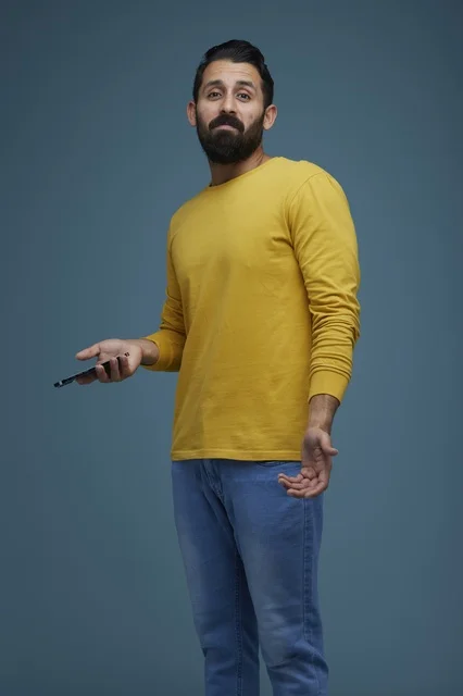 شاب سعودي يمسك هاتفاً ذكياً بتعبير وجه مرتبك