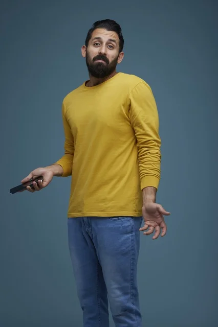Saudi Man Shrugging with Smartphone on Blue Background