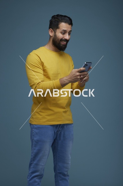 شاب سعودي يستخدم الهاتف الذكي بقميص أصفر