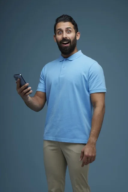 Shocked Saudi Man with Smartphone on Blue Background