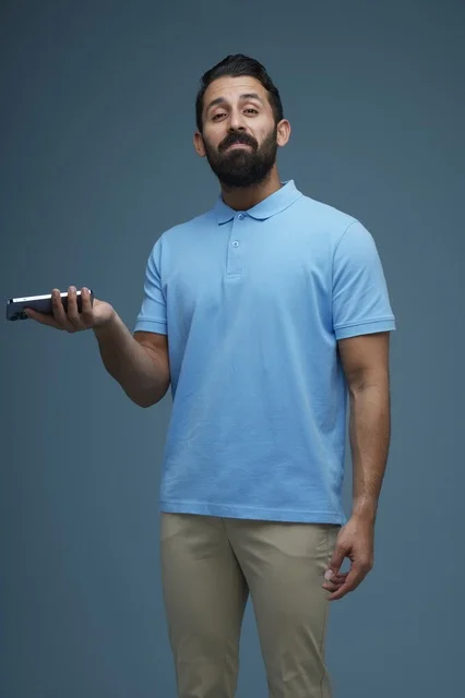 Saudi Man Holding Smartphone on Blue Studio Background