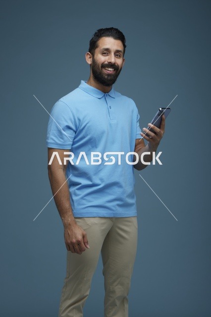 شاب سعودي يحمل هاتف ذكي في استوديو تصوير