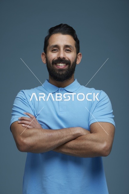 بورتريه شاب سعودي مبتسم يرتدي ملابس كاجوال خلفية زرقاء