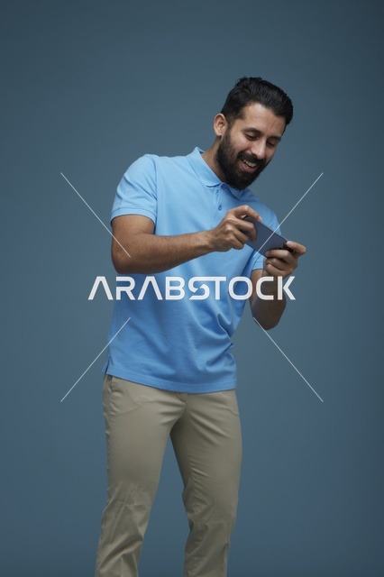 شاب سعودي يلعب لعبة على الهاتف الذكي في الاستوديو