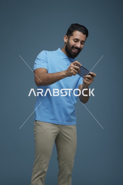 شاب سعودي يلعب ألعاب الجوال بملابس كاجوال زرقاء