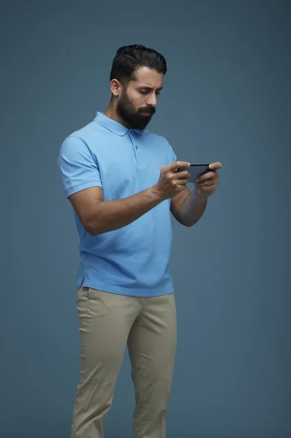 Saudi Man Playing Mobile Game on Blue Background