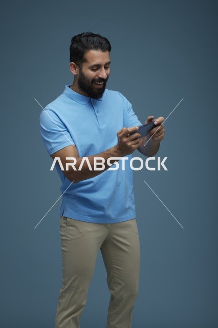 شاب سعودي يلعب بهاتفه بملابس كاجوال
