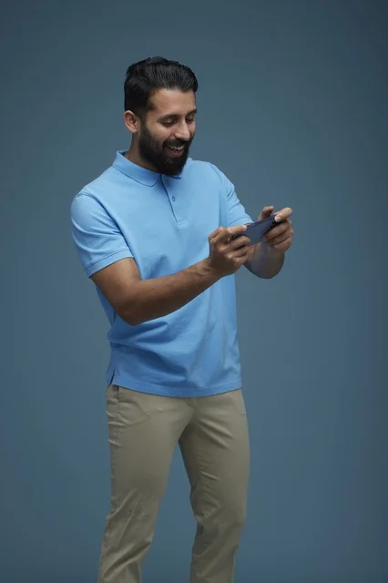 Saudi Man Playing Mobile Game in Blue Polo