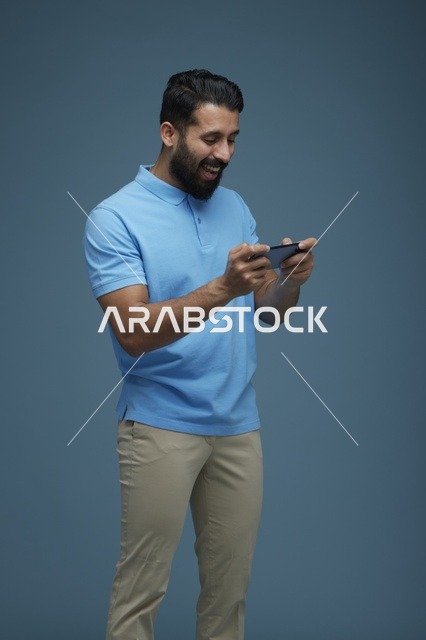 شاب سعودي يلعب لعبة هاتف ذكي بملابس كاجوال