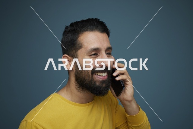 شاب سعودي يتحدث بالهاتف الذكي بملابس كاجوال صفراء