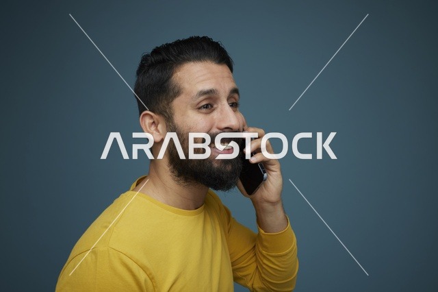 شاب سعودي يتحدث بالهاتف الذكي بملابس كاجوال صفراء