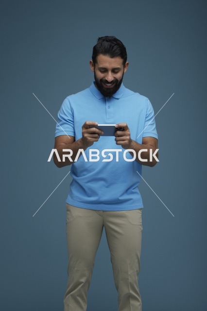 شاب سعودي يلعب بهاتفه الذكي بملابس كاجوال