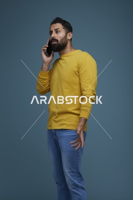 شاب سعودي يتحدث بالهاتف الذكي بقميص أصفر ملابس كاجوال