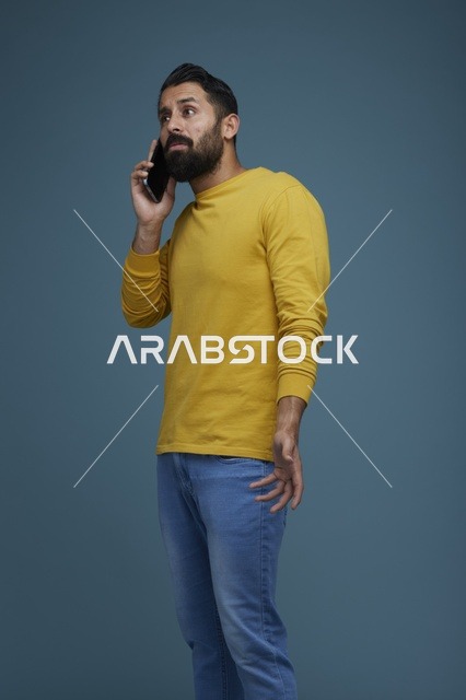 شاب سعودي يتحدث عبر الهاتف بملابس كاجوال صفراء