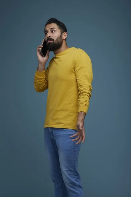 شاب سعودي يتحدث عبر الهاتف بملابس كاجوال صفراء