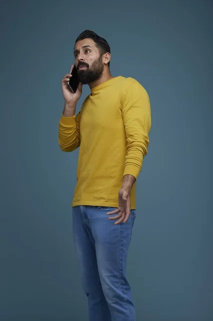 شاب سعودي بملابس كاجوال يتحدث عبر الهاتف الذكي