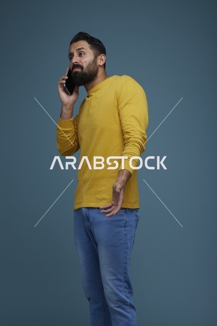 شاب سعودي يتحدث بالهاتف الذكي بقميص أصفر كاجوال