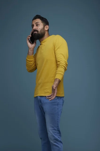شاب سعودي يتحدث بالهاتف الذكي بقميص أصفر كاجوال