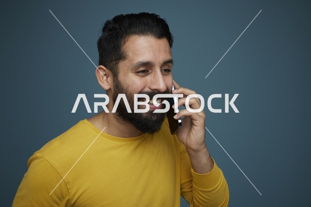 شاب سعودي يتحدث بالهاتف الذكي بقميص أصفر