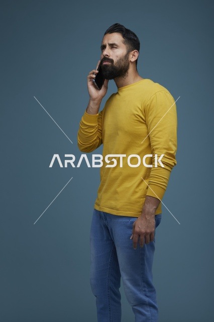 شاب سعودي يتحدث بالهاتف الذكي بملابس كاجوال