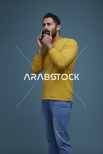 شاب سعودي يتحدث بالهاتف الذكي بقميص أصفر