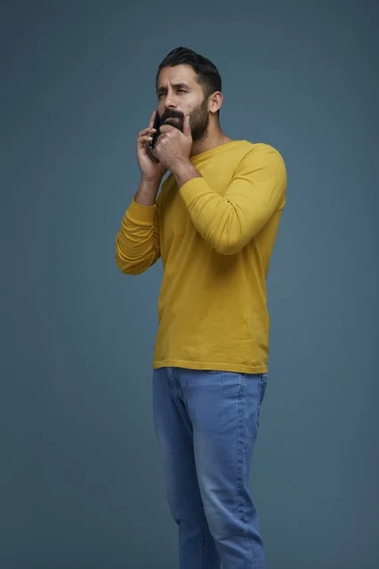 شاب سعودي يتحدث بالهاتف الذكي بقميص أصفر