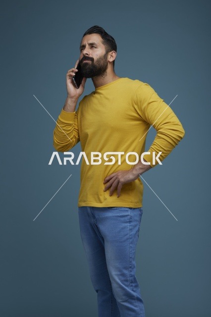 شاب سعودي يتحدث عبر الهاتف الذكي بملابس كاجوال صفراء