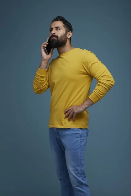 شاب سعودي يتحدث عبر الهاتف الذكي بملابس كاجوال صفراء