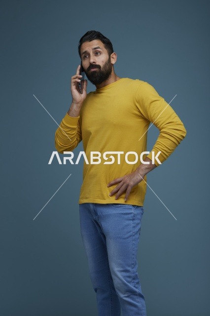 شاب سعودي يتحدث بالهاتف الذكي بملابس كاجوال صفراء