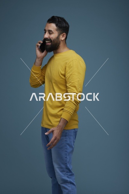 شاب سعودي يتحدث بالهاتف الذكي استوديو خلفية زرقاء