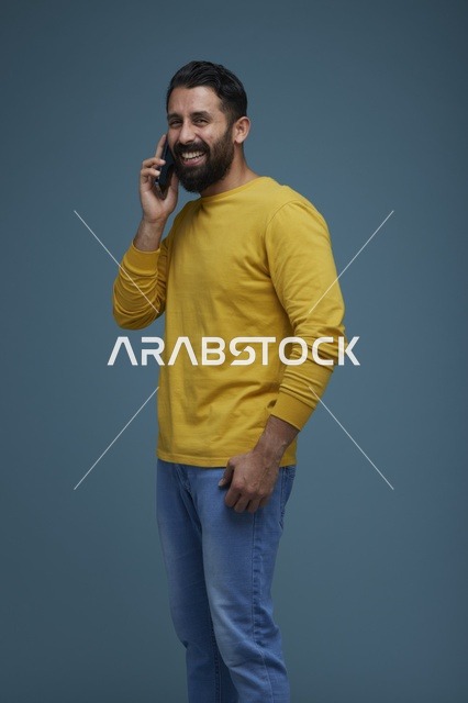 شاب سعودي يتحدث عبر الهاتف الذكي بملابس كاجوال صفراء