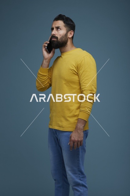 شاب سعودي يتحدث عبر الهاتف الذكي بملابس كاجوال