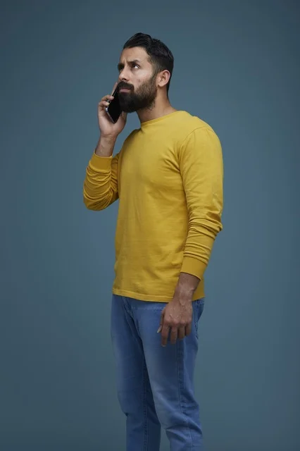 شاب سعودي يتحدث عبر الهاتف الذكي بملابس كاجوال