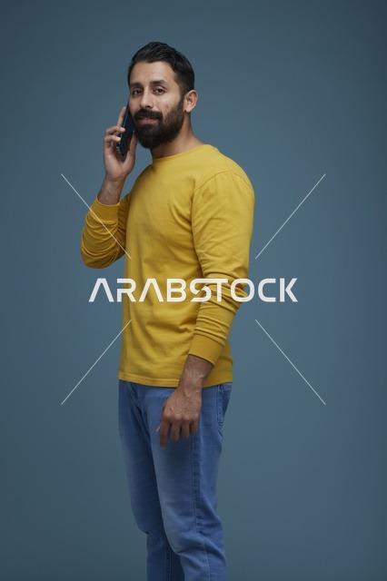 شاب سعودي يتحدث عبر الهاتف الذكي بملابس كاجوال صفراء
