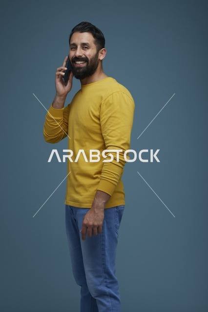 شاب سعودي يتحدث عبر الهاتف الذكي بملابس كاجوال