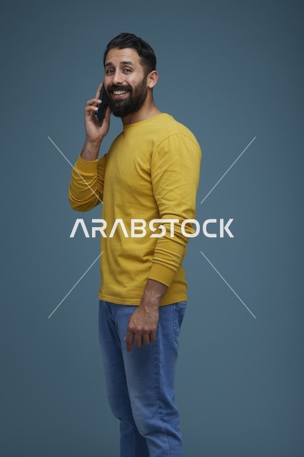شاب سعودي يتحدث بالهاتف الذكي بقميص أصفر