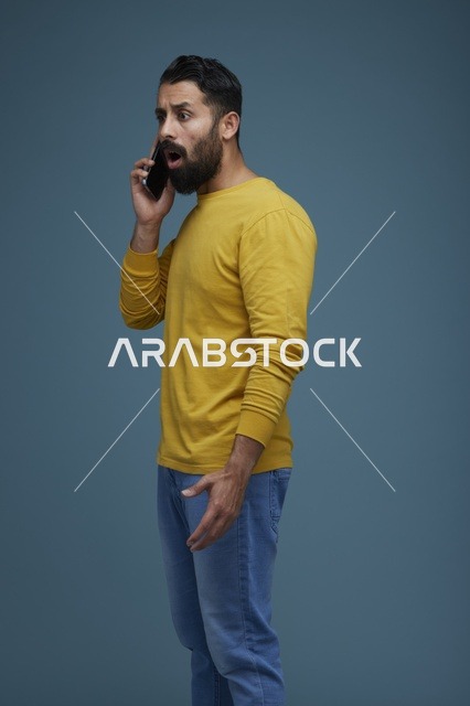 شاب سعودي متفاجئ يتحدث عبر الهاتف بملابس كاجوال