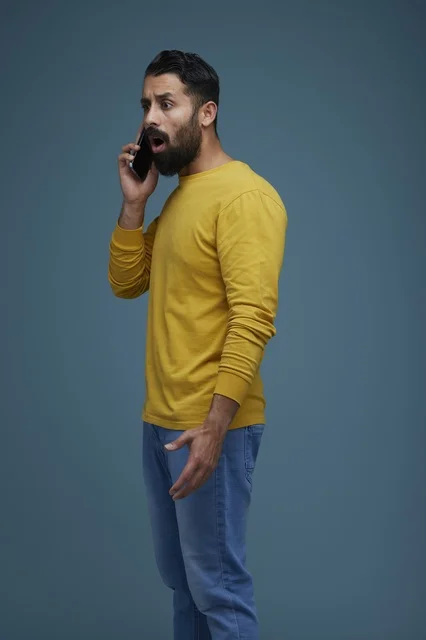 شاب سعودي متفاجئ يتحدث عبر الهاتف بملابس كاجوال