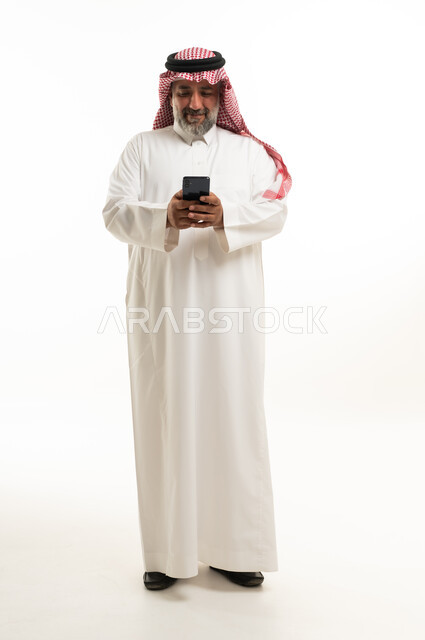 رجل سعودي في منتصف العمر يستخدم هاتف ذكي في الاستوديو