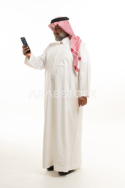 Saudi Man in Traditional Thobe Using Smartphone